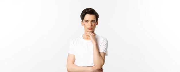Immagine di un uomo gay attraente in maglietta bianca con glitter sul viso e guardando la fotocamera sta serio