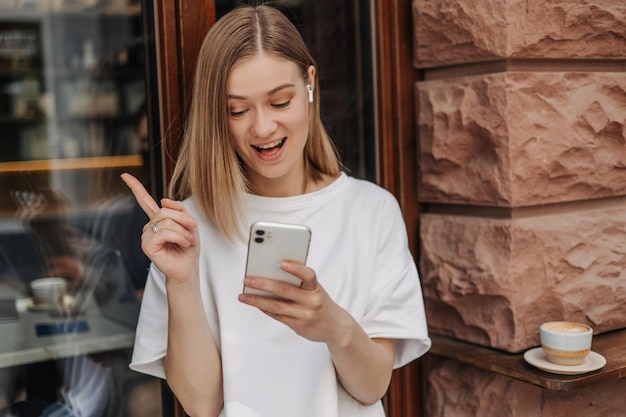 Immagine di una bella donna con il telefono che mostra il dito in su