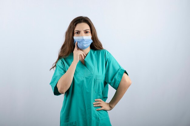 Immagine di una bella infermiera pensierosa in uniforme verde che guarda lontano