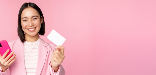 Immagine di una donna d'affari asiatica felice sorridente che mostra il pagamento con carta di credito online sull'applicazione per smartphone