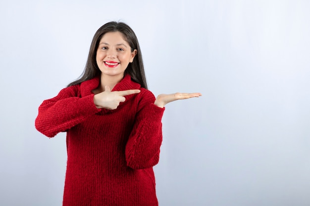 Immagine di una giovane donna in maglione rosso che mostra la mano su sfondo bianco white