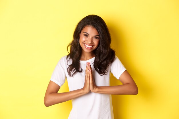 Immagine di una graziosa donna afroamericana che ringrazia e sorride stringendosi le mani