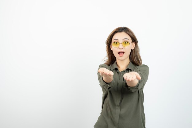 Immagine di una ragazza adorabile con gli occhiali che aprono i palmi delle mani su bianco. Foto di alta qualità