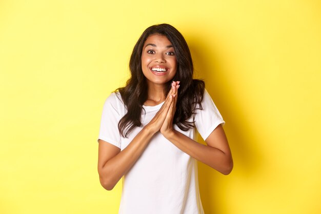 Immagine di una ragazza afroamericana felice e compiaciuta che applaude le mani e sembra eccitata ringraziando