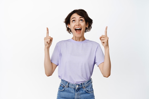 Immagine di una ragazza stupita e super felice che guarda con il volto affascinato e stupito, indicando il logo, promozione di vendita, mostrando pubblicità, sfondo bianco.