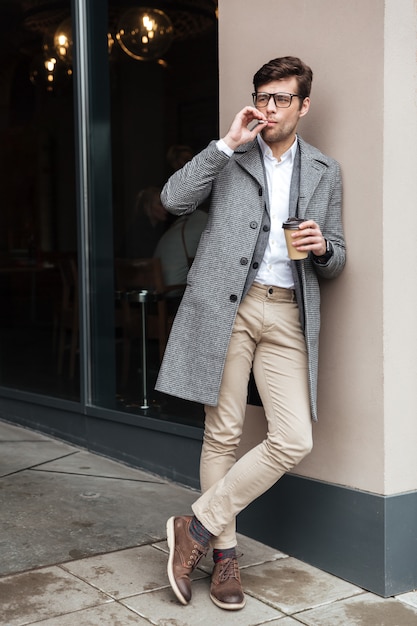Immagine integrale dell'uomo d'affari in occhiali e cappotto