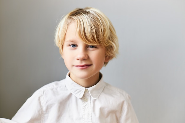 Immagine isolata del ragazzo caucasico dagli occhi blu allegro emotivo con capelli biondi con espressione facciale giocosa. Bambini, spontaneità, infanzia felice ed emozioni positive
