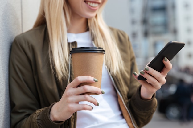 Immagine potata della donna bionda che per mezzo dello smartphone