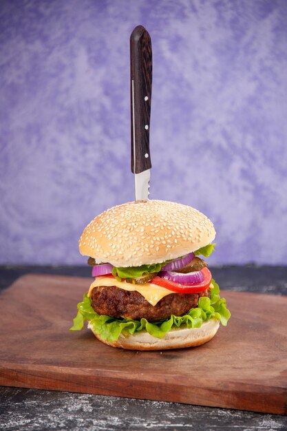 Immagine ravvicinata di coltello in gustoso panino di carne su tagliere di legno su superficie di ghiaccio isolata con spazio libero