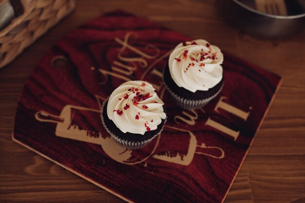 Immagine ravvicinata di due muffin neri fatti in casa con molta crema bianca sopra