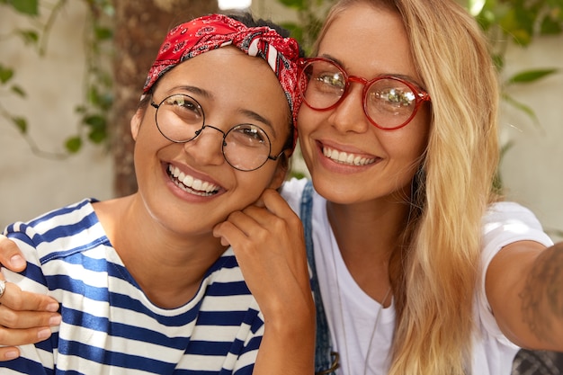 Immagine ravvicinata di due ragazze amichevoli di razza mista posano per selfie, dimostrano amicizia interrazziale