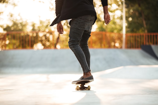 Immagine ritagliata di un giovane skateboarder adolescente in azione