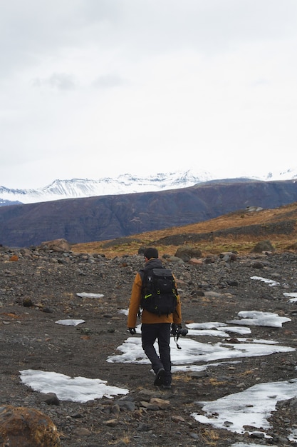 Immagine verticale di un escursionista con una macchina fotografica sulle colline coperte di neve in Islanda