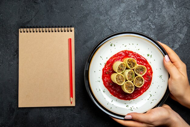 Impasto di vista dall'alto con fette di carne affettata con salsa di pomodoro sulla scrivania grigia