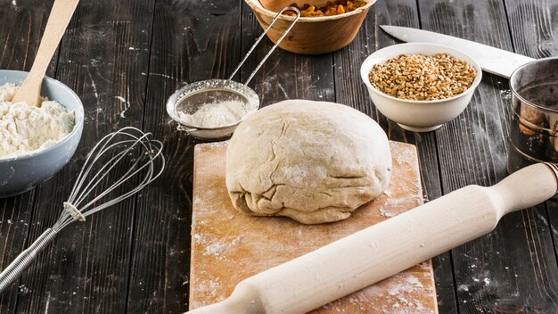 Impasto per il pane sul tagliere con mattarello con ingredienti