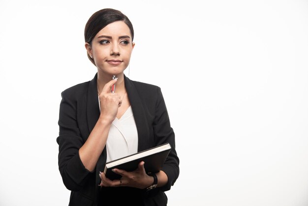 Impiegata femminile con libro pensando al prossimo progetto. Foto di alta qualità