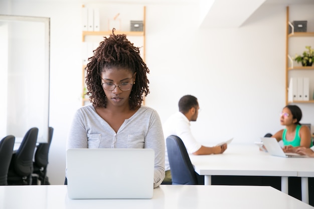 Impiegato afroamericano emozionante serio che lavora al computer