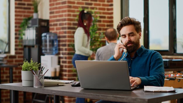 Impiegato dell'azienda che risponde a una telefonata su rete fissa al lavoro aziendale, parlando con il manager sulla linea telefonica del cavo dell'ufficio. Conversazione remota con il numero di telefono al lavoro, chiamata di lavoro.