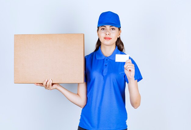 Impiegato della donna di consegna in scatola di carta del mestiere della tenuta dell'uniforme con la carta.