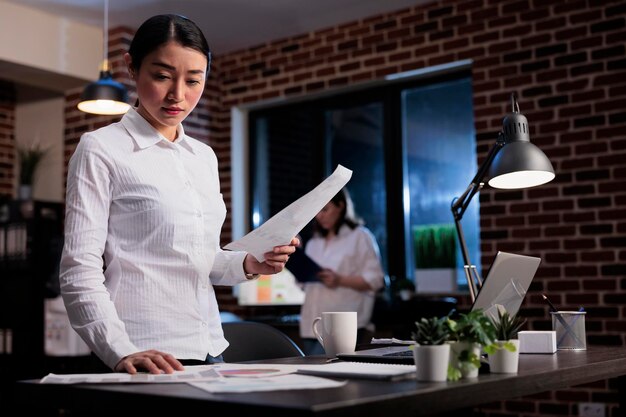 Impiegato della società di marketing con appunti di scartoffie che esaminano la documentazione contabile nell'area di lavoro dell'ufficio. Giovane imprenditore adulto che legge i termini e le condizioni del contratto di affare.