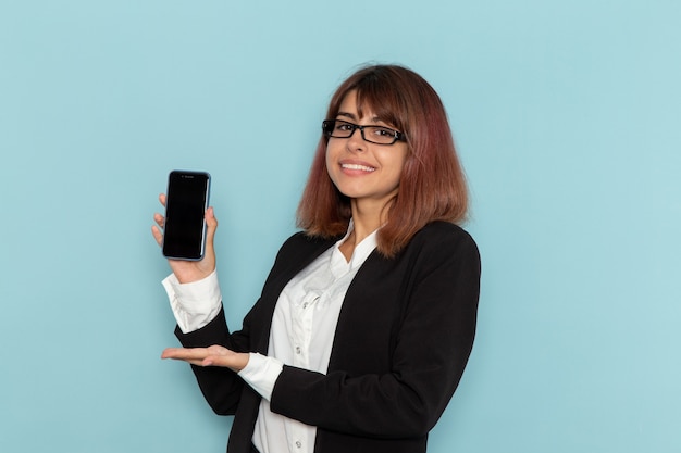 Impiegato di ufficio femminile di vista frontale che tiene il suo smartphone sulla superficie blu