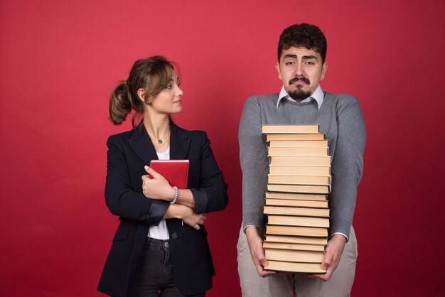 Impiegato femminile che esamina uomo con il mazzo di libri