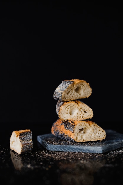 Impilati di fetta di pane su ardesia di roccia contro sfondo nero