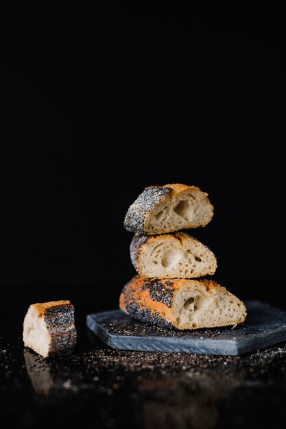 Impilati di fetta di pane su ardesia di roccia contro sfondo nero