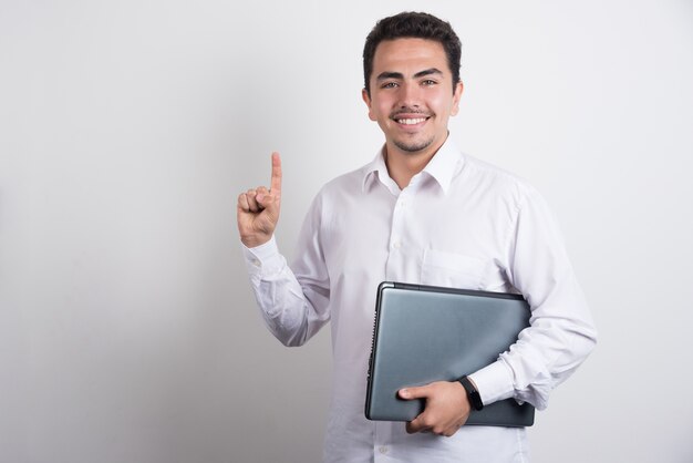 Imprenditore azienda laptop e rivolto verso l'alto su sfondo bianco.