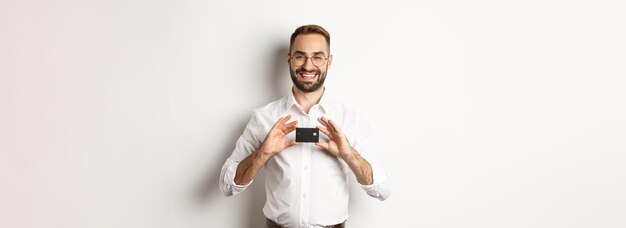 Imprenditore bello in possesso di una carta sorridente soddisfatto in piedi su sfondo bianco