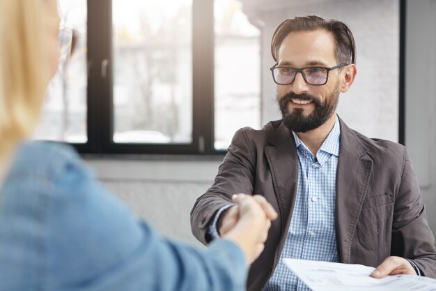 Imprenditore e imprenditrice si stringono la mano dopo aver firmato con successo il contratto