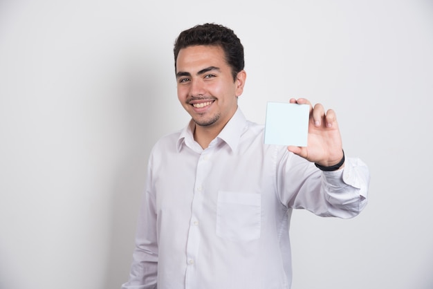 Imprenditore mostrando memo pad su sfondo bianco.