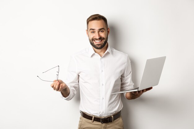 Imprenditore professionista fiducioso facendo lavoro sul computer portatile, guardando soddisfatto, in piedi