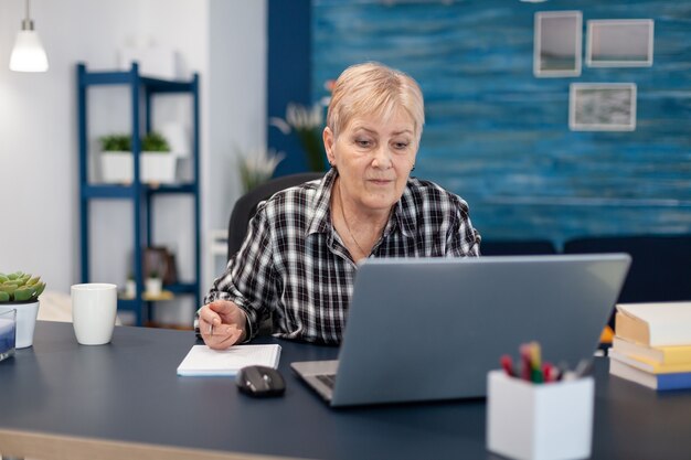 Imprenditore senior che legge dal computer portatile senza occhiali