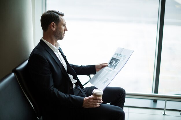 Imprenditore un caffè durante la lettura del giornale in sala d'attesa