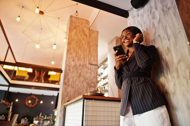 Imprenditrice afroamericana in un caffè con il telefono cellulare Ragazza nera che ha resto