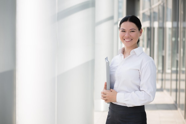 Imprenditrice asiatica sorridente con file nelle sue mani.