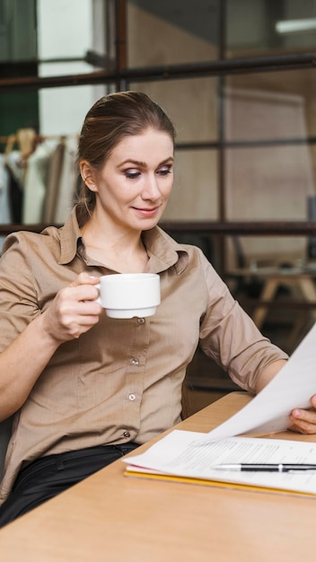 Imprenditrice con caffè e leggere documenti