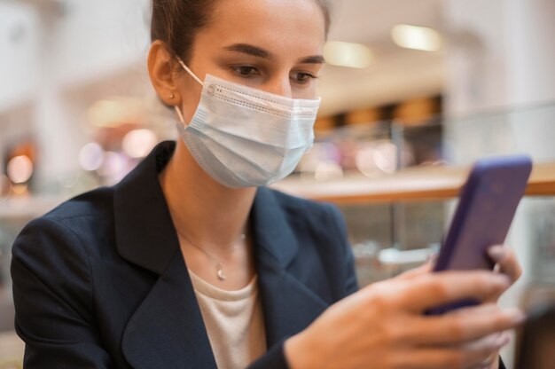 Imprenditrice con mascherina medica guardando il suo telefono