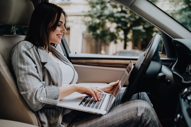 Imprenditrice con un laptop nella sua auto in strada