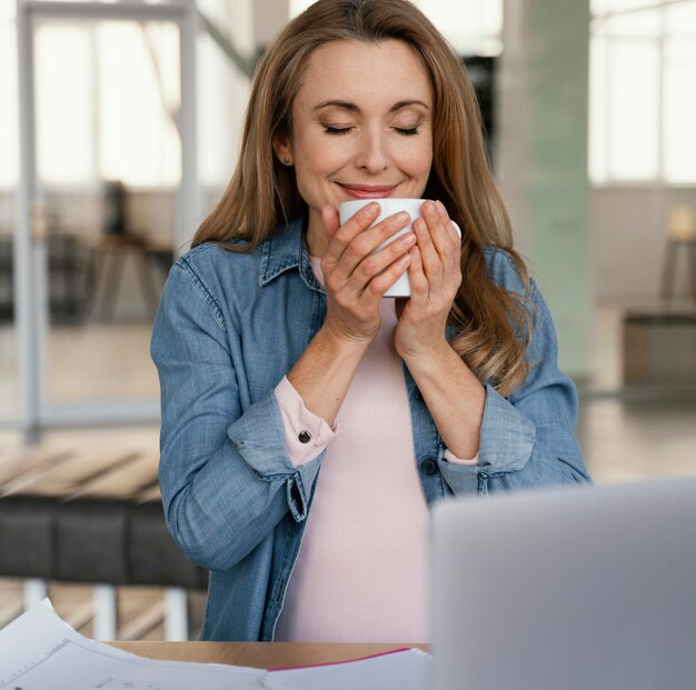 Imprenditrice di smiley annusando il suo caffè del mattino