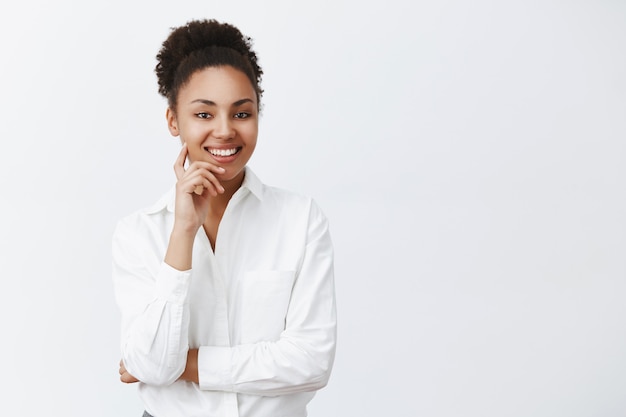 Imprenditrice di successo dalla carnagione scura di bell'aspetto che ascolta con un sorriso educato e amichevole dipendente, fa domanda per un nuovo lavoro, intervista la persona, tiene il dito sulla guancia e sorride ampiamente