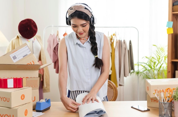 Imprenditrice donna asiatica vende vestiti per l'imballaggio al proprietario di una piccola impresa di avvio del cliente PMI