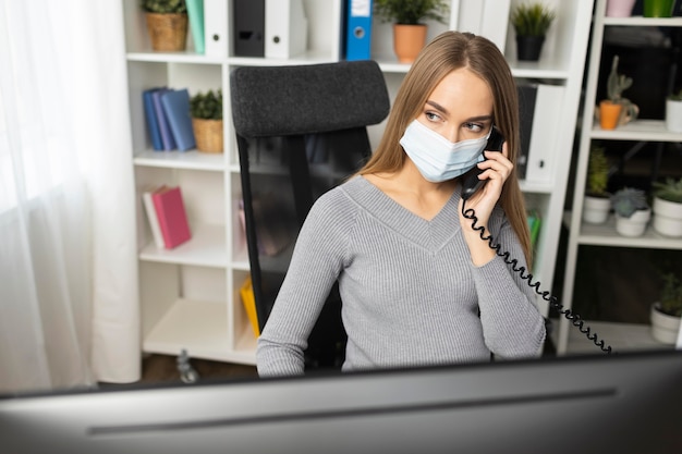 Imprenditrice incinta parlando al telefono mentre indossa la mascherina medica