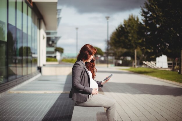 Imprenditrice incinta utilizzando la tavoletta digitale