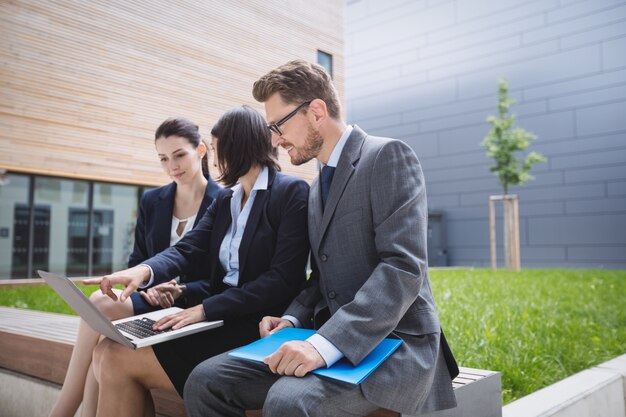 Imprenditrice seduta con i colleghi e utilizzando laptop