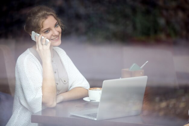 Imprenditrice sorridente parlando al telefono in un negozio di caffè