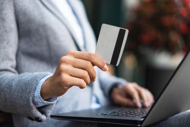 Imprenditrice tenendo la carta di credito durante l'utilizzo di laptop