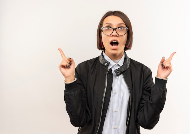 Impressionato giovane ragazza della call center con gli occhiali alla ricerca e rivolto verso l'alto isolato su bianco con spazio di copia