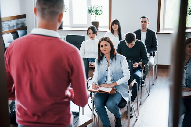 In camicia rossa. Gruppo di persone alla conferenza di lavoro in aula moderna durante il giorno